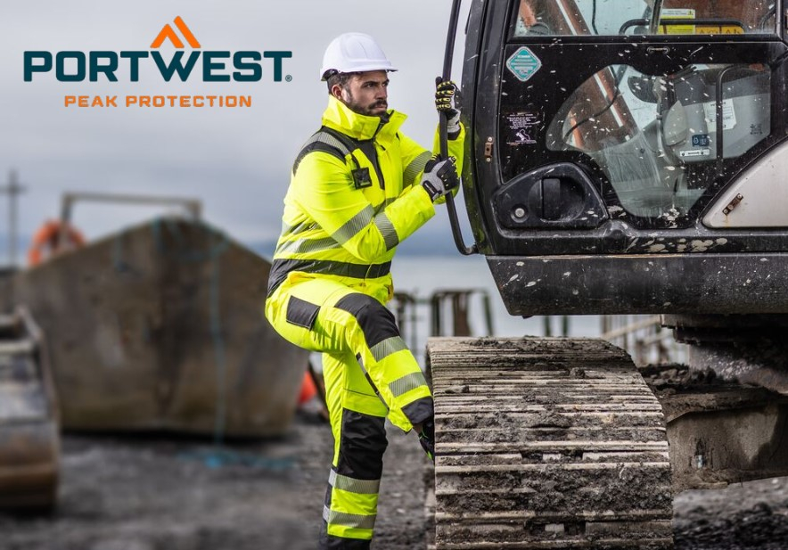 Ein Arbeiter in einem leuchtend gelben Warnschutzanzug mit reflektierenden Streifen, einem weißen Schutzhelm und Handschuhen steigt in eine Baumaschine. Im Hintergrund ist eine Baustellenumgebung mit Baugeräten und grauem Himmel zu sehen. Oben links im Bild befindet sich das Logo von "Portwest" mit dem Slogan "Peak Protection". Ein Link zu unserer Auswahl verschiedener Arbeitsoveralls ist hinterlegt.